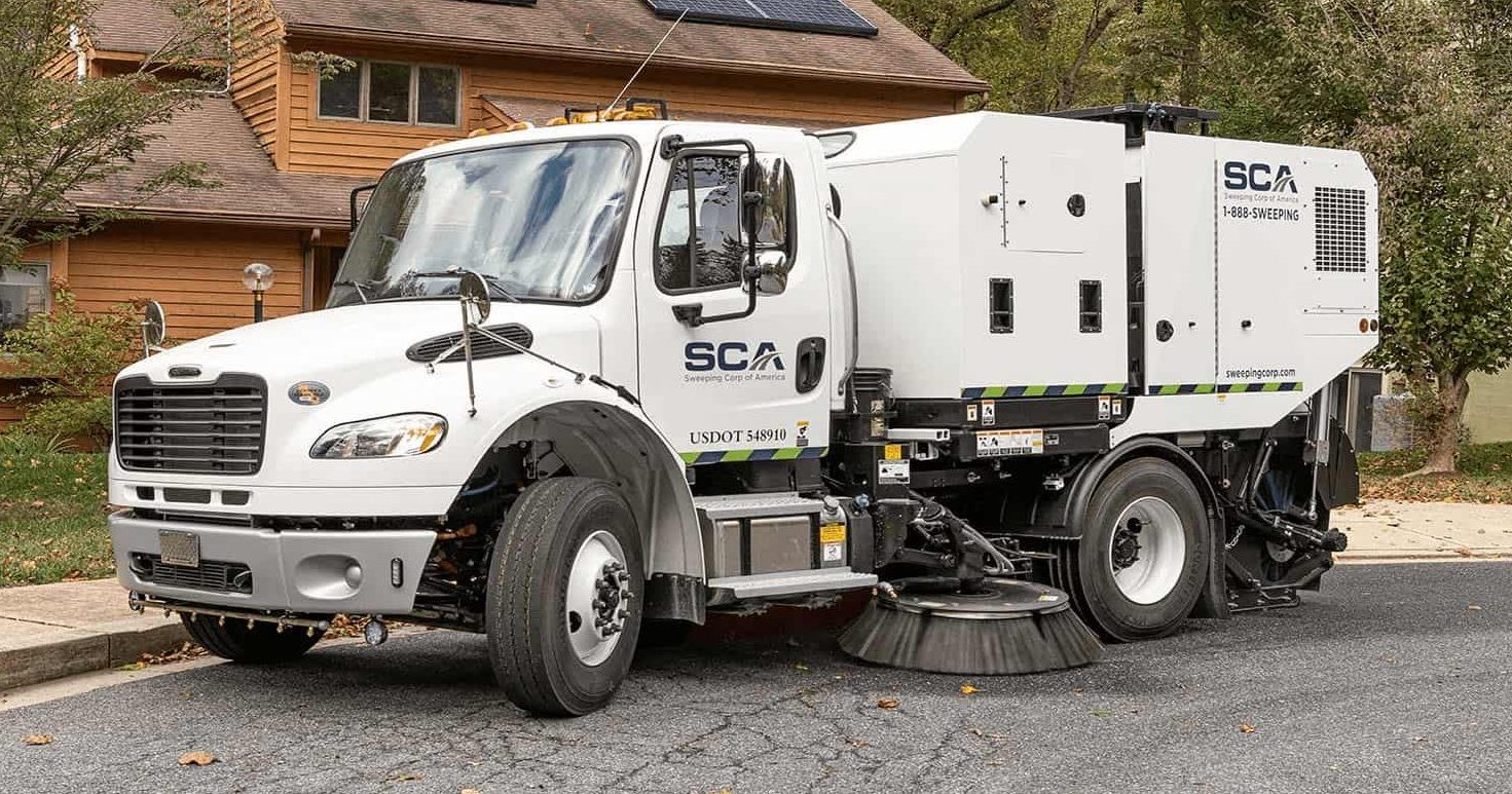 A power sweeping truck cleaning a residential street