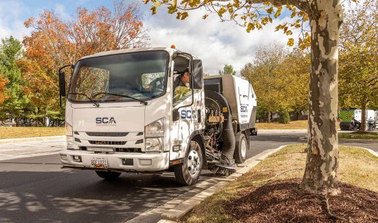 A sweeping truck cleaning a shopping center parking lot