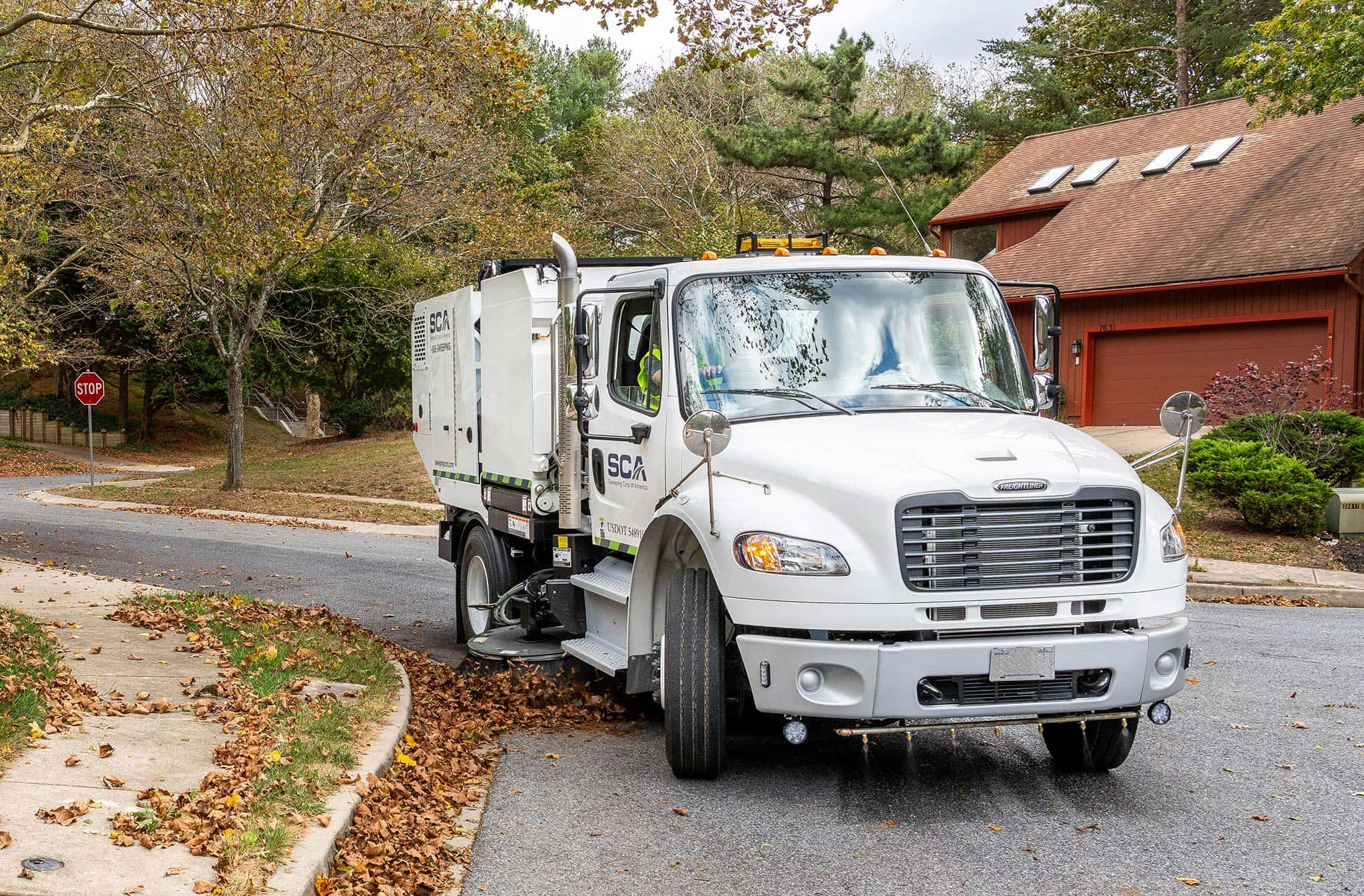 A sweeping truck cleaning leaves in a residential neighborhood