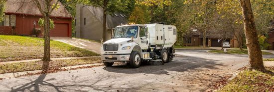 A sweeper truck cleaning a residential neighborhood