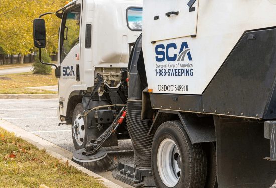 A sweeping truck cleaning a parking lot