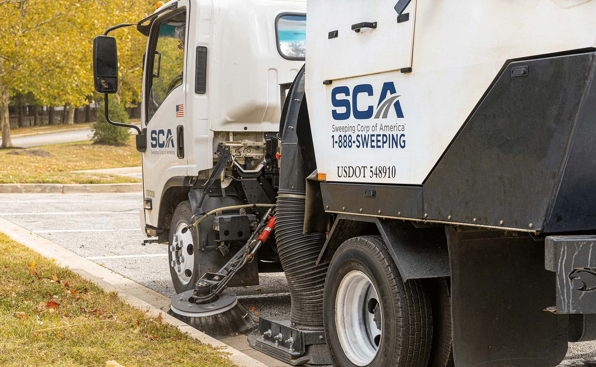 A sweeping truck cleaning a parking lot